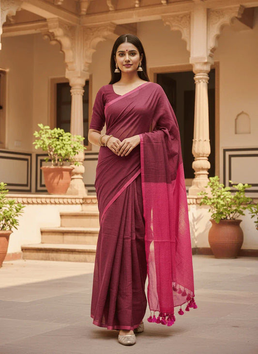 Elegant maroon saree with pink border and tassels, worn in traditional courtyard setting
