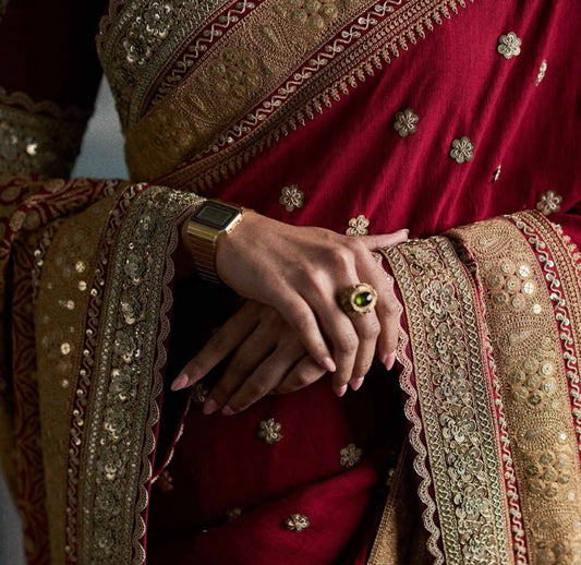 Close-up of a person wearing a red saree with gold and brown embroidery.