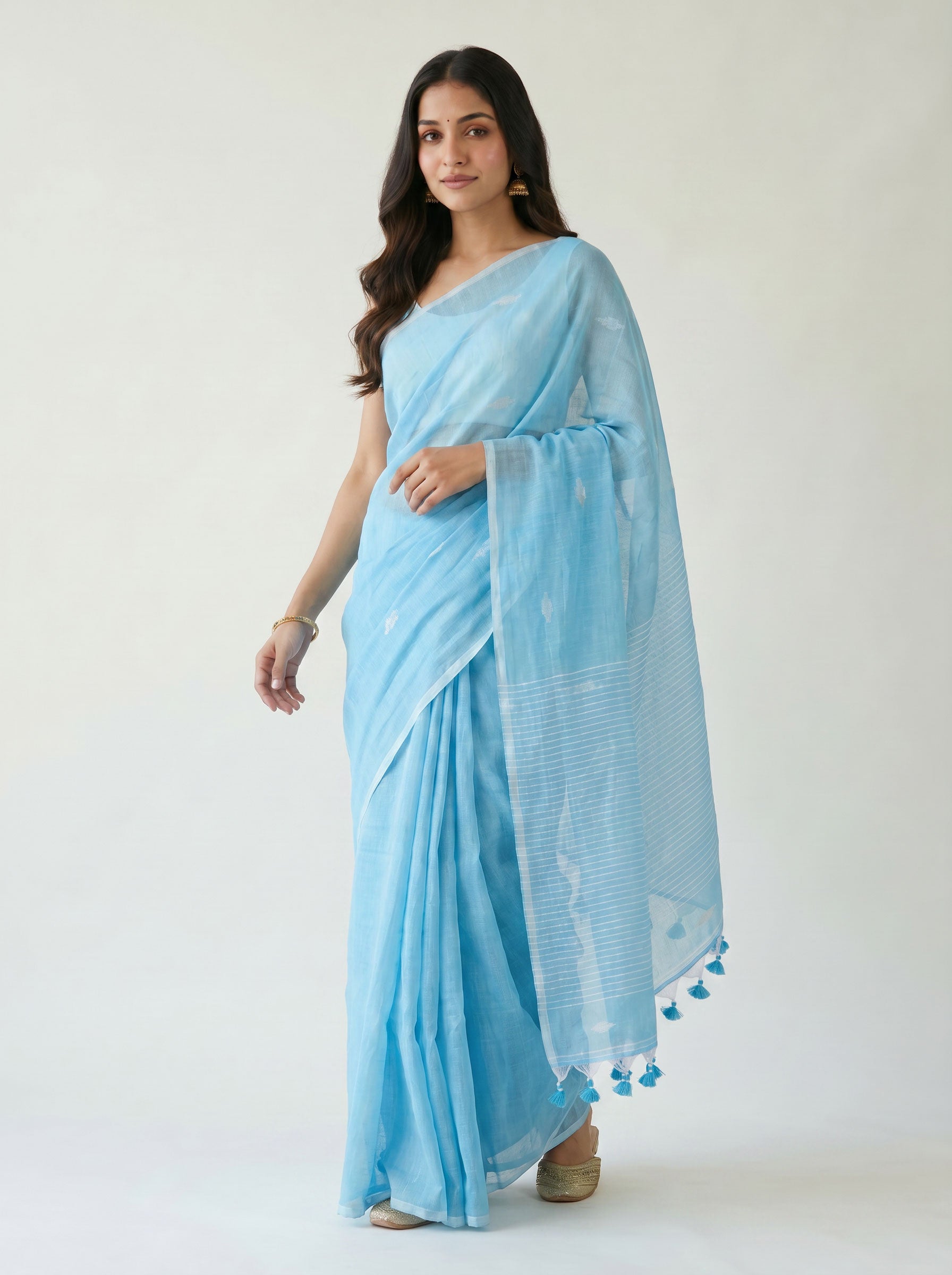 Woman wearing a light blue saree with a white background